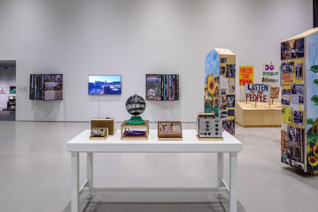 Image: Installation shot of works contributed by (in foreground) Basketshop: mixed use objects by SEELE, (to the left) Park and Pool: Anything But the World (No Homo) and Contributions and Proposal Posters; (to the right) Storefronts: installation of People Moving. Installation view of Artist-Run Spaces, May 27 – September 11, 2022, Contemporary Arts Center, Cincinnati, OH. Photo: Wes Battoclette. Image courtesy of CAC.