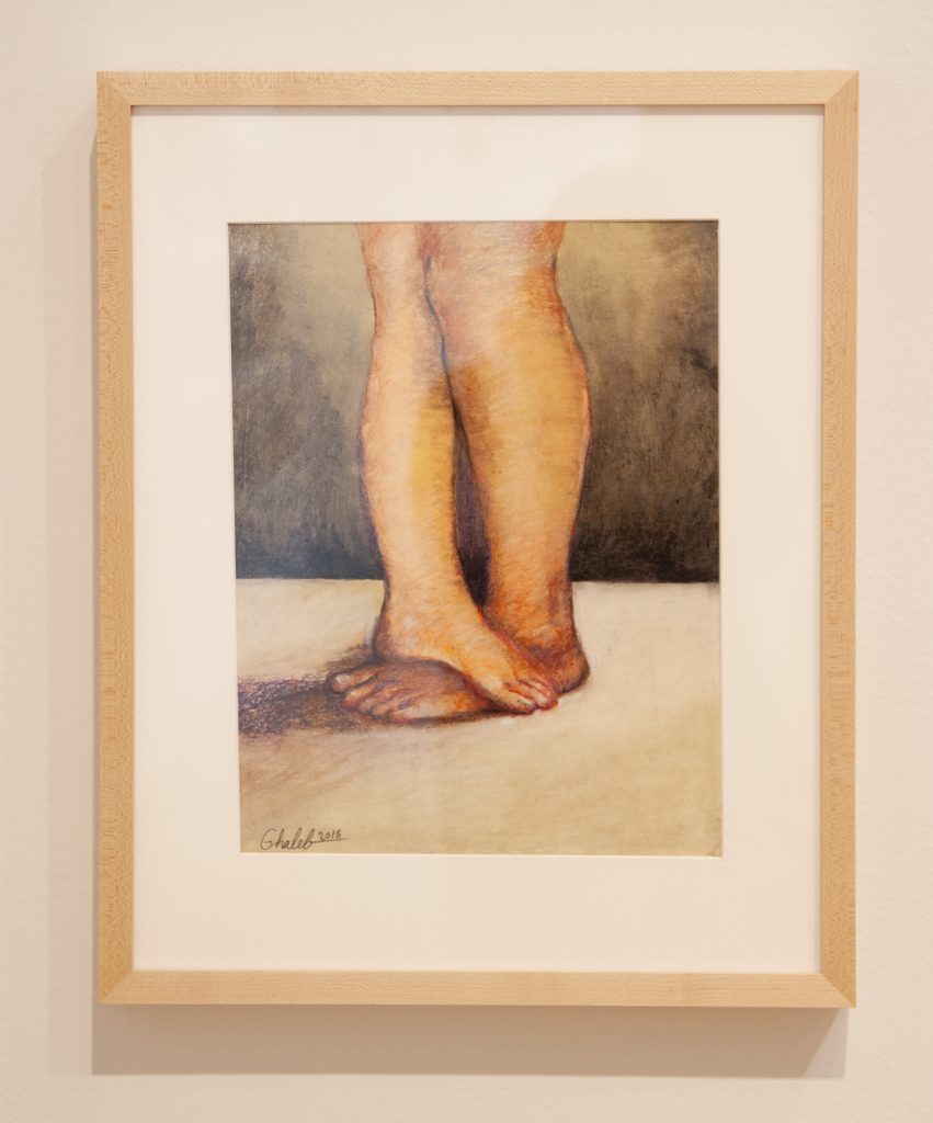 Image: Untitled by Ghaleb al-Bihani, 2016. A painting features two legs from the knees down to the feet, one foot standing perpendicular across the other on a white surface in a black backdrop. Photograph by Robert Chase Heishman. Courtesy of the DePaul Art Museum.