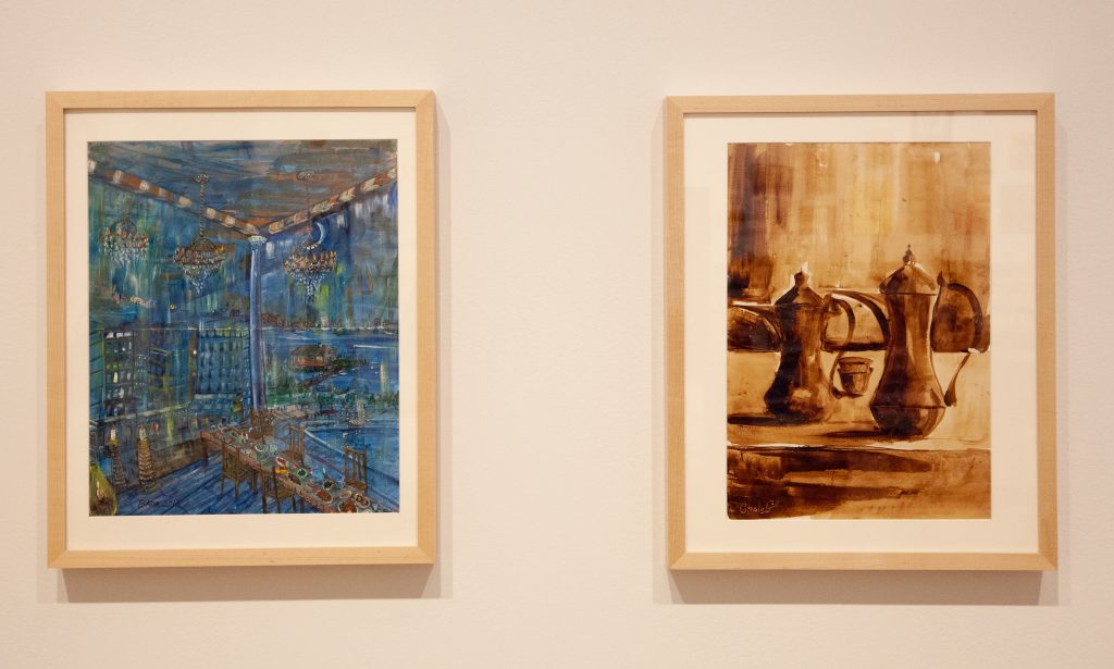 Image: Two paintings framed in light wood. The left one, Untitled by Ahmed Badr-Rabbani, 2016, depicts a dining room with chandeliers in a bright blues and golds. The right one, Untitled by Ghaleb al-Bihani, 2016, depicts two handled tea carafes and two tea cups in a spectrum of gold and browns. Photograph by Zoey Dalbert. Courtesy of the DePaul Art Museum.
