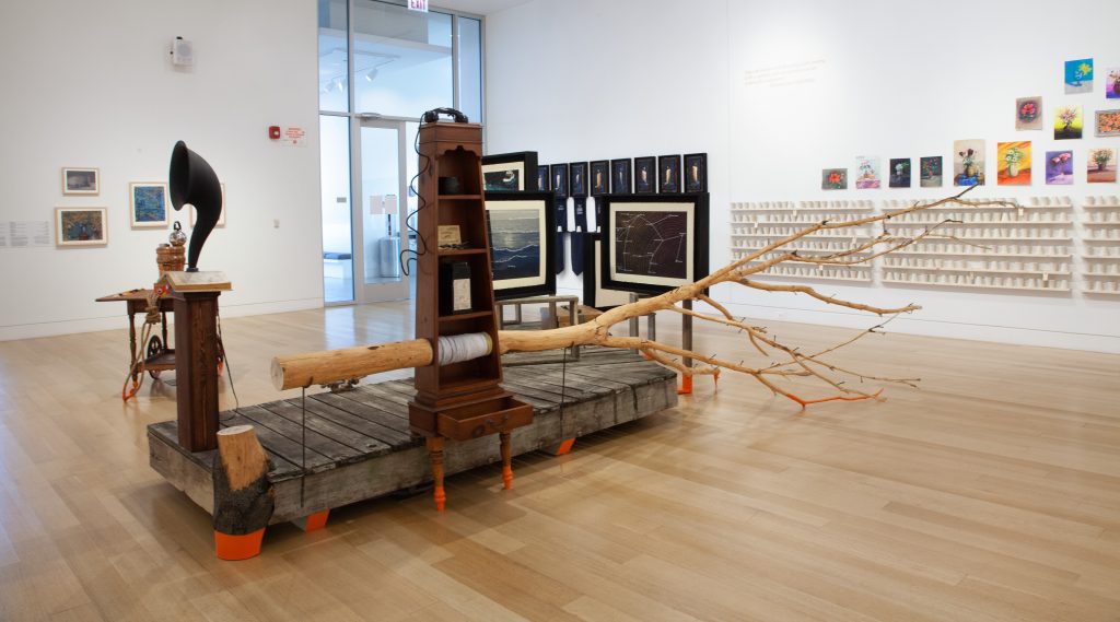 Image: A view of the gallery floor. In the center is a pier with various audio accoutrement built on top of it. Photograph by Zoey Dalbert. Courtesy of the DePaul Art Museum.