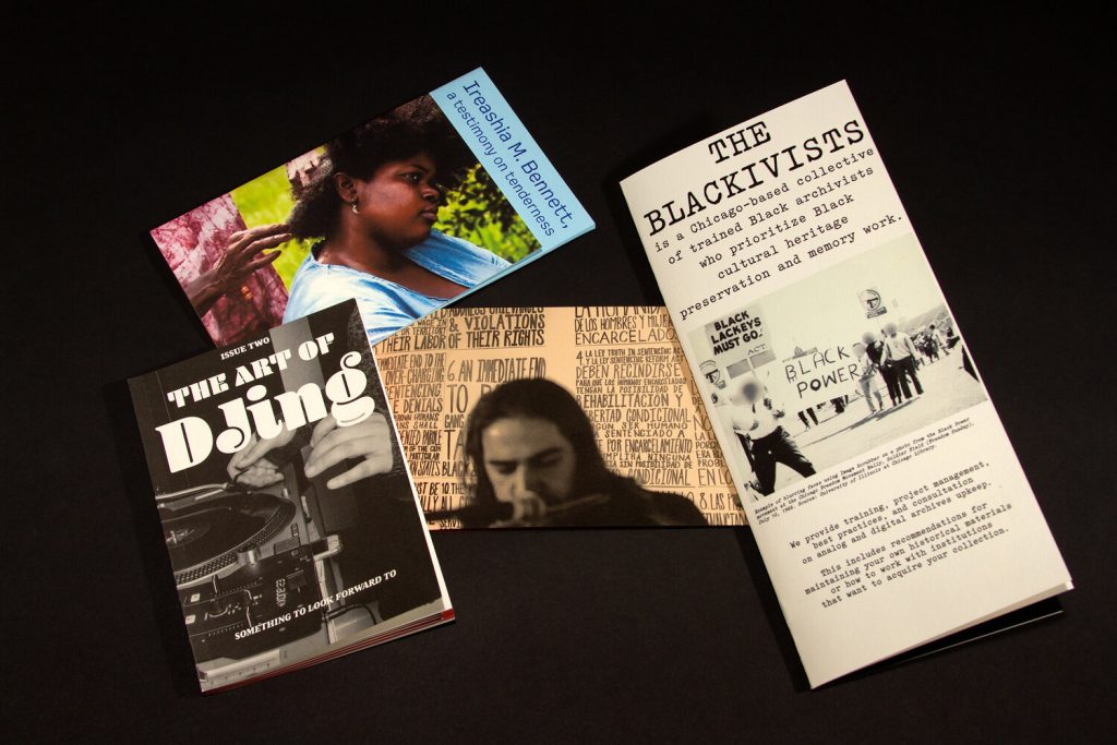 Image: The first three issues of Something to look forward to. The title on issue one is blue text on blue paper and reads “Ireashia M. Bennett, a testimony on tenderness.” Issue two is a small greyscale book with bright orange pages, and a cover that says “The Art o DJing”. Issue three is a two-book set, with one white trifold brochure with black text that says “The Blackivists is a Chicag-based collective of trained Black archivists who prioritize Black cultural heritage preservation and memory work.” The other book in the set is cream colored with black text and says “Artists + Archivists for Liberation.” Image courtesy of Candor Arts.