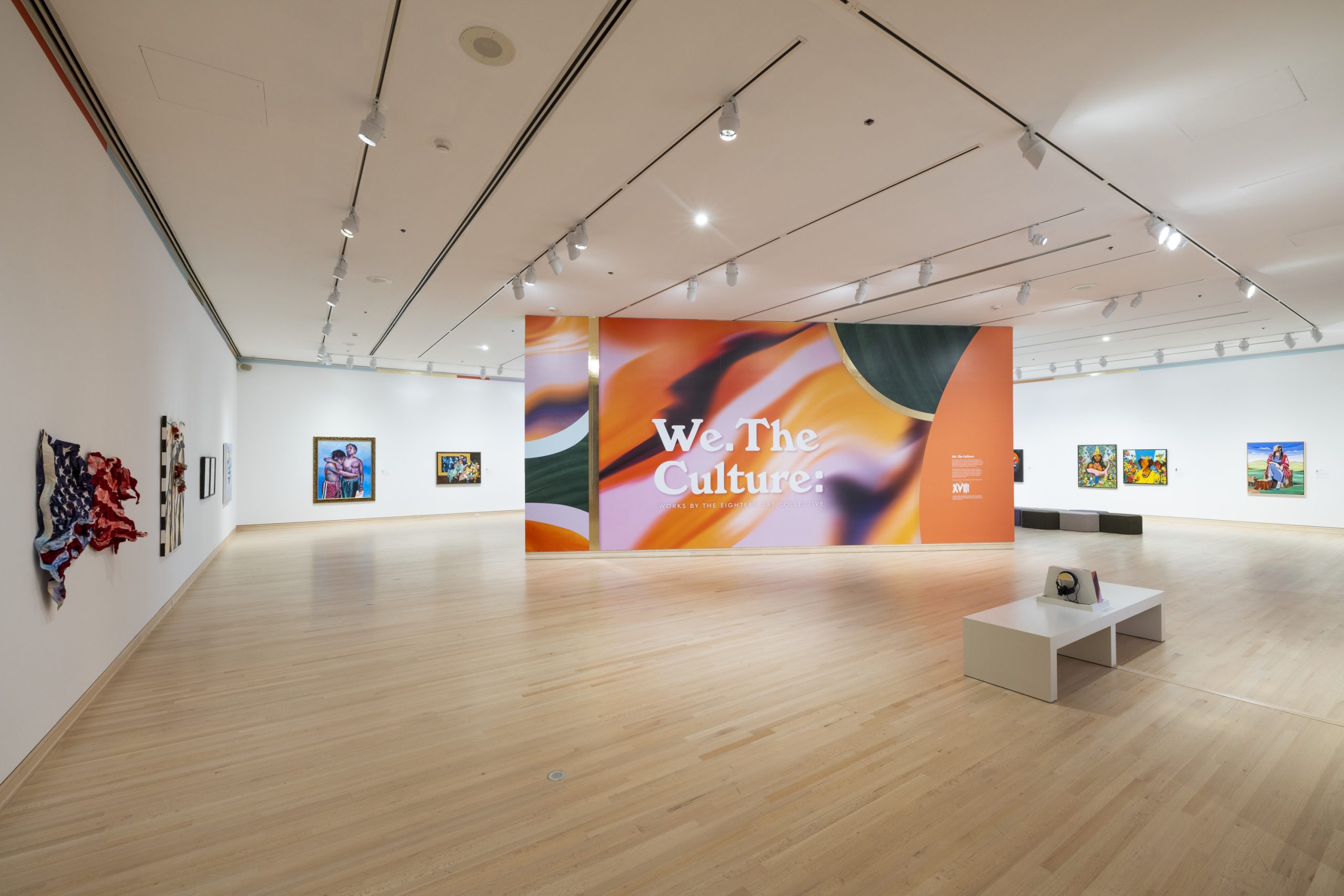 Image: Installation view of We. The Culture: Works by The Eighteen Art Collective in the June M. McCormack Forefront Galleries, September 23, 2022–September 24, 2023. Floating wall with the show's title surrounded by paintings on white walls in a square-shaped room. Photo courtesy of the Indianapolis Museum of Art at Newfields.