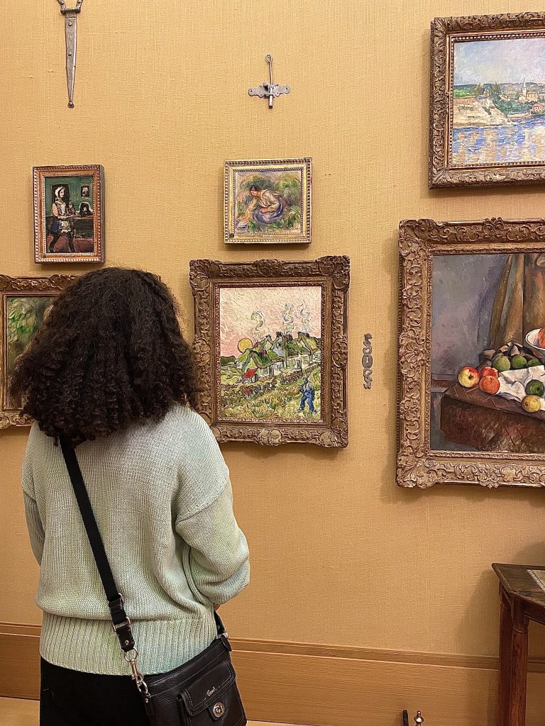Image: The author is facing a Van Gogh painting of a French hillside village at the Barnes Foundation in Philladelphia. Image courtesy of Chenoa Baker.