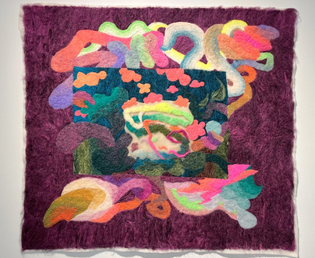 Image: Rachel Collier, Kids In The Wood, 2022. A smaller image of tufted, multicolored shapes resembling clouds and other natural shapes is framed by a tufted, eggplant-colored background with intestine-like, neon shapes woven behind the image. Courtesy of the artist.