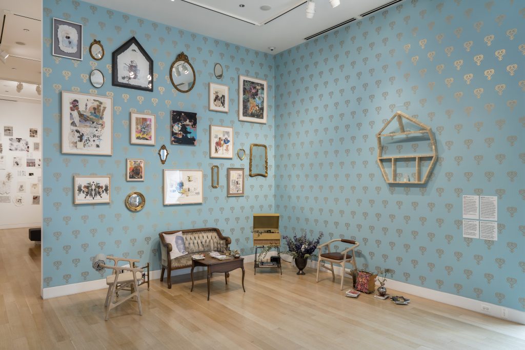 Image: Installation view, Krista Franklin, Library of Love, 2014/2022. Sky blue wall with golden heart pattern (design by Stephen Flemister) displays a grouping of pictures and mirrors above a loveseat and other furniture. Photo by Dabin Ahn. Courtesy of DePaul Art Museum.