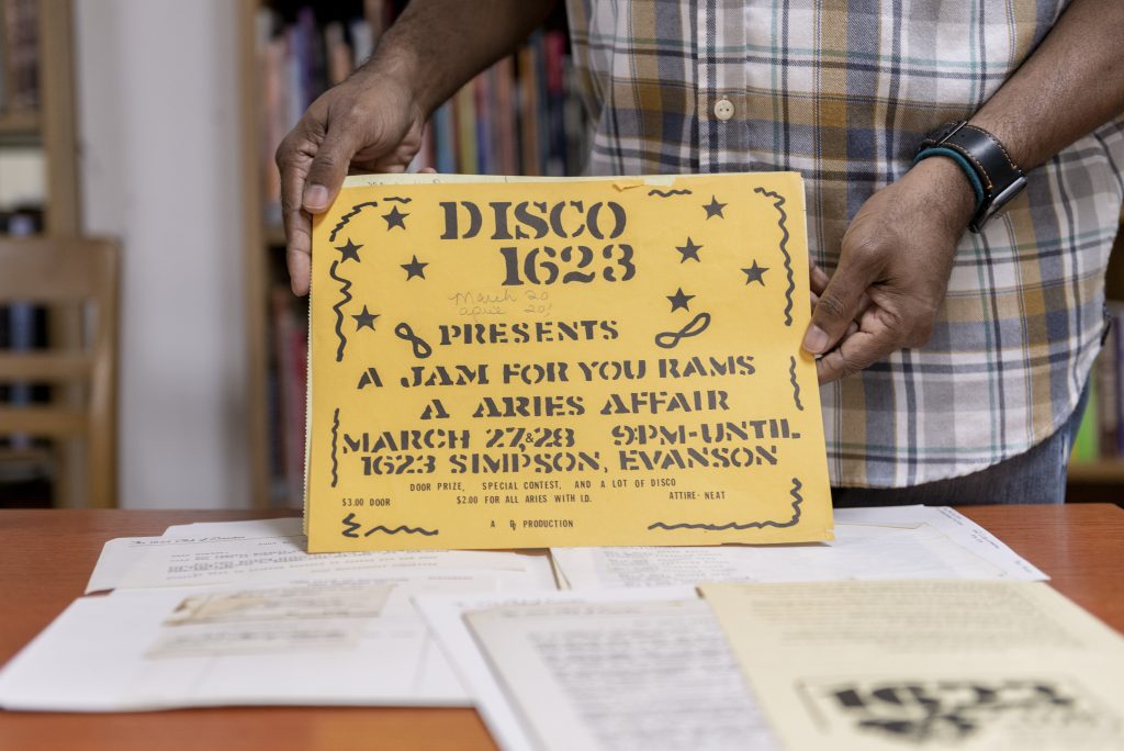 Image: Dino holds up a yellow text-heavy flyer to the camera. The document reads: "1623 Presents A Jam For You Rams A Aries Affair March 27 & 28 9pm-until. 1623 Simpson, Evanson. Door Prize, Special Contest, and A lot of Disco. $3.00 Door. $2.00 for all Aries with I.D. Attire-neat." Photo by Ryan Edmund Thiel.