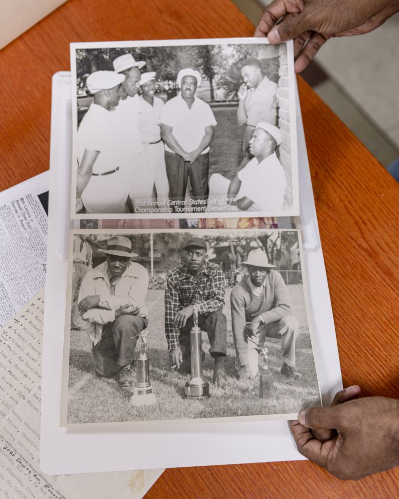 Image: Two black and white photographs are displayed on top of a wooden table. The top image features six men gathered together and text at the bottom of the image reads: "21st Annual Central States Golf Championship Tournament Denver Colo. July 18-25 1954." The bottom image features three men kneeling in grass behind golf trophies. Photo by Ryan Edmund Thiel.