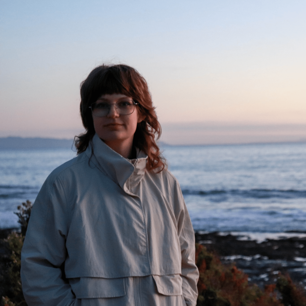 Image: Livy Snyder standing in a coat. Behind her is a large body of water.