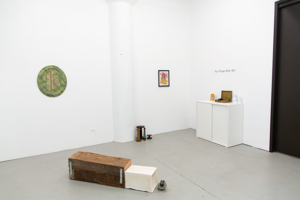 Image: Exhibition shot of For Those Who Toil (2023) at Purple Window Gallery. Michael Chambers' large sculptural piece sits center frame. In the background two of Millicent Kennedy's pieces hang equidistant on the gallery's wall. Image by Amy Shelton.