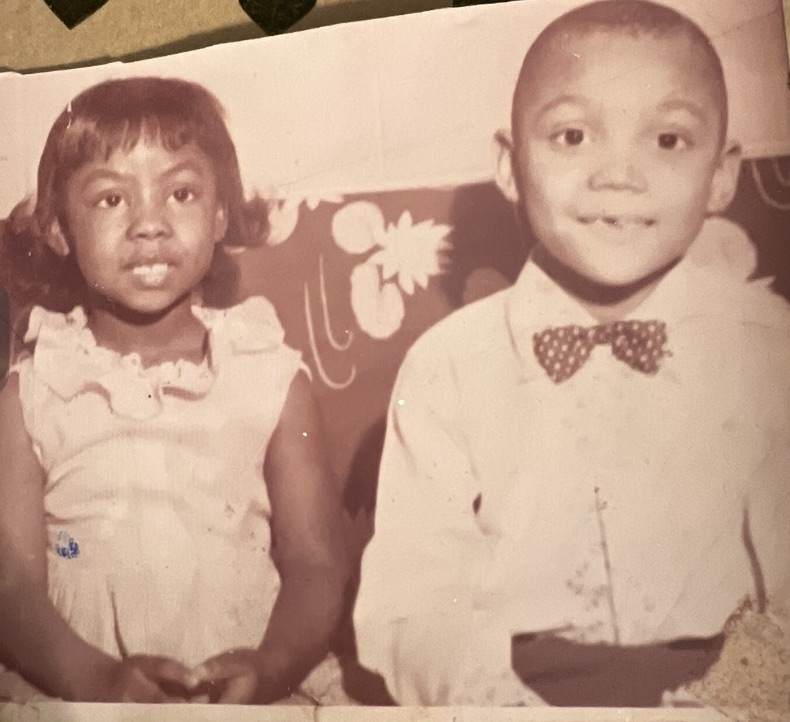 Image: A black and white photo shows a toddler-aged, Vanita, sitting next to her brother, Ben. They are 14th months apart in age. Image courtesy of the Green family.