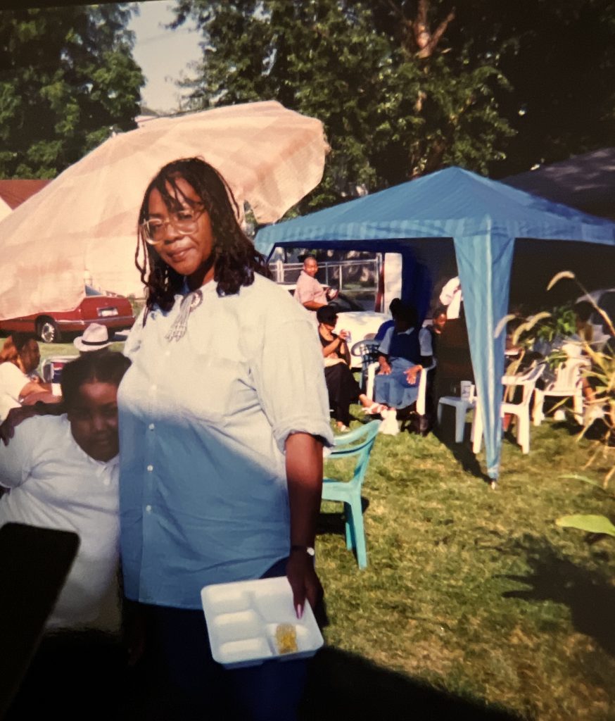 Image: Vanita, partially shaded, embraces her youngest daughter Carmen in a park at a family reunion. Image courtesy of the Green family.