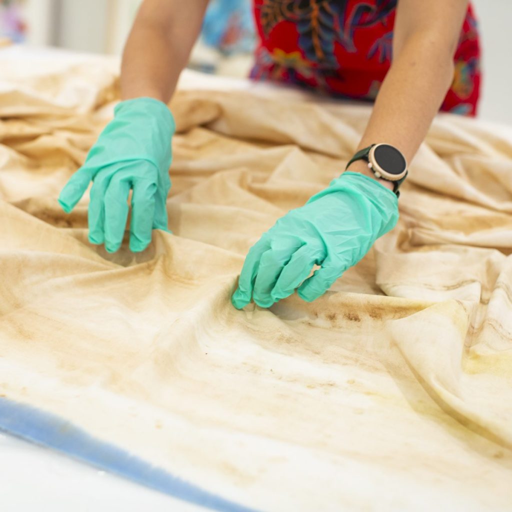 A photo of Natasha Mijares touching a textile object from the DePaul Art Museum's collection. Photograph by Kristie Kahns.