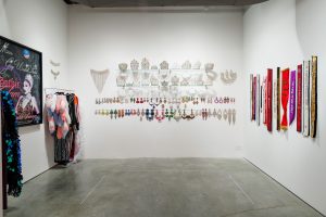 Image: An installation view of Faleasha Savage's Behind Closed Doors, 2022. Garments, jewelry, sashes, and crowns.