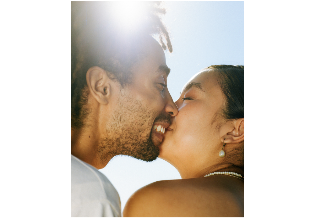 Image: A photograph of Francine Almeda and Antonio Robles Levine half smiling, half kissing with the sun shining behind them. Photo courtesy of the artists.