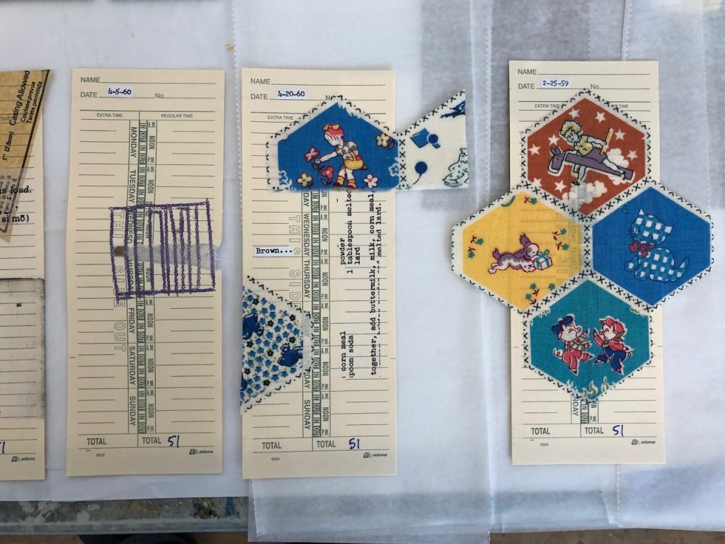 Image: Time Cards for Mothers, 2021. L to R: Mending, Nurturing, Childcare. Collage on timecards, with paper, fabric, and machine stitching. Three-time cards are on a table. The first is the one that’s torn and sewn back together, described above. The next two have stiffened fabric with printed hexagons, each hexagon having a design inside of it. The fabric is for children and looks vintage, but may be a reproduction.  The hexagons extend beyond the edges of the timecard. For the total number of hours, each time card has “51.” Courtesy of the artist.