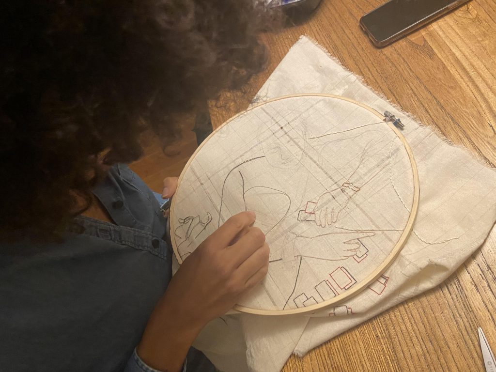 Image: Alexandra is seen working on an embroidery that's in progress. Photo courtesy of the artists.