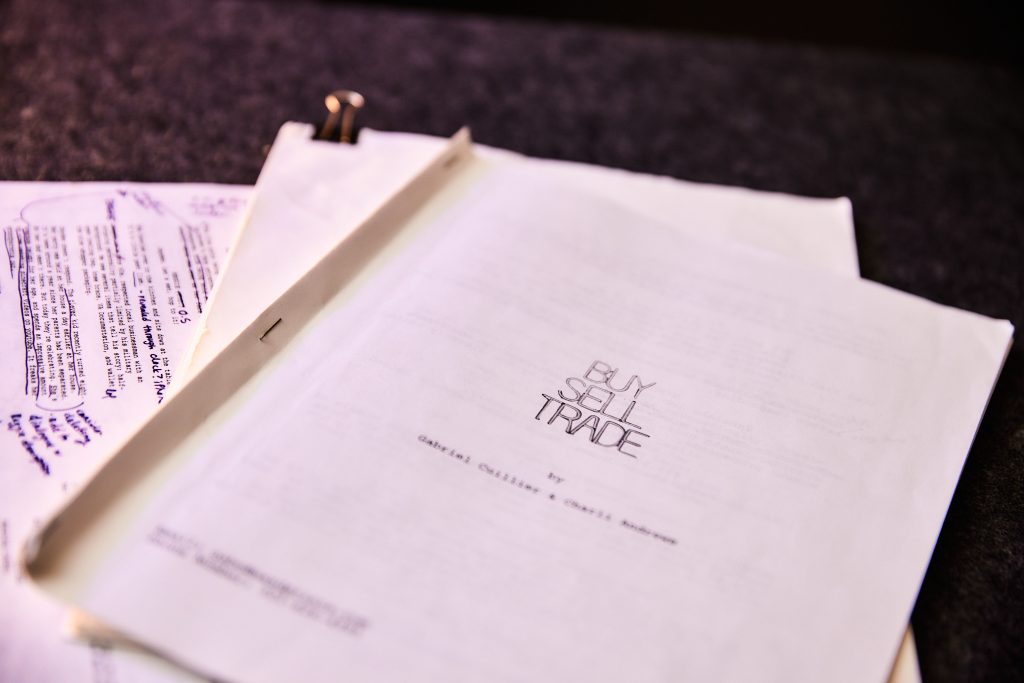 Image: The cover of the script "Buy Sell Trade." A stack of white paper stapled together with the words "Buy Sell Trade" printed on the top page. Photo by Sarah K. Joyce.