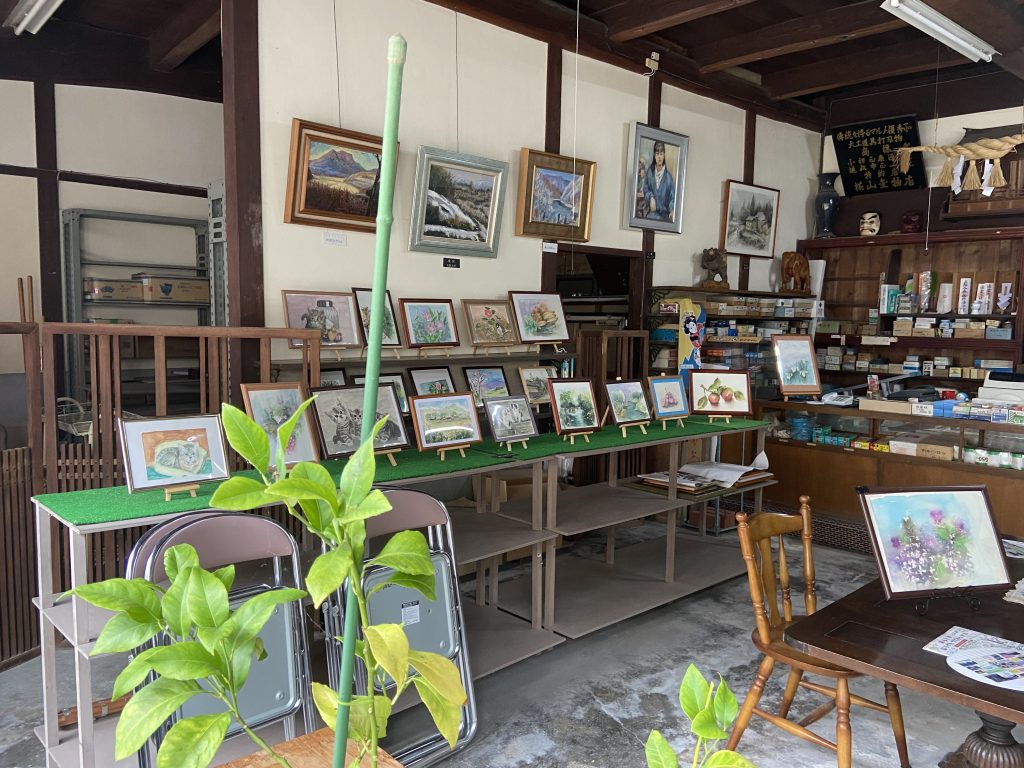 Image: Art space Yokoyama in Japan's Hiroshima prefecture. Paintings are presented on utility shelves, walls, and other surfaces in a former hardware store. Art supplies crowd the old checkout counter. Image courtesy of the artist. 