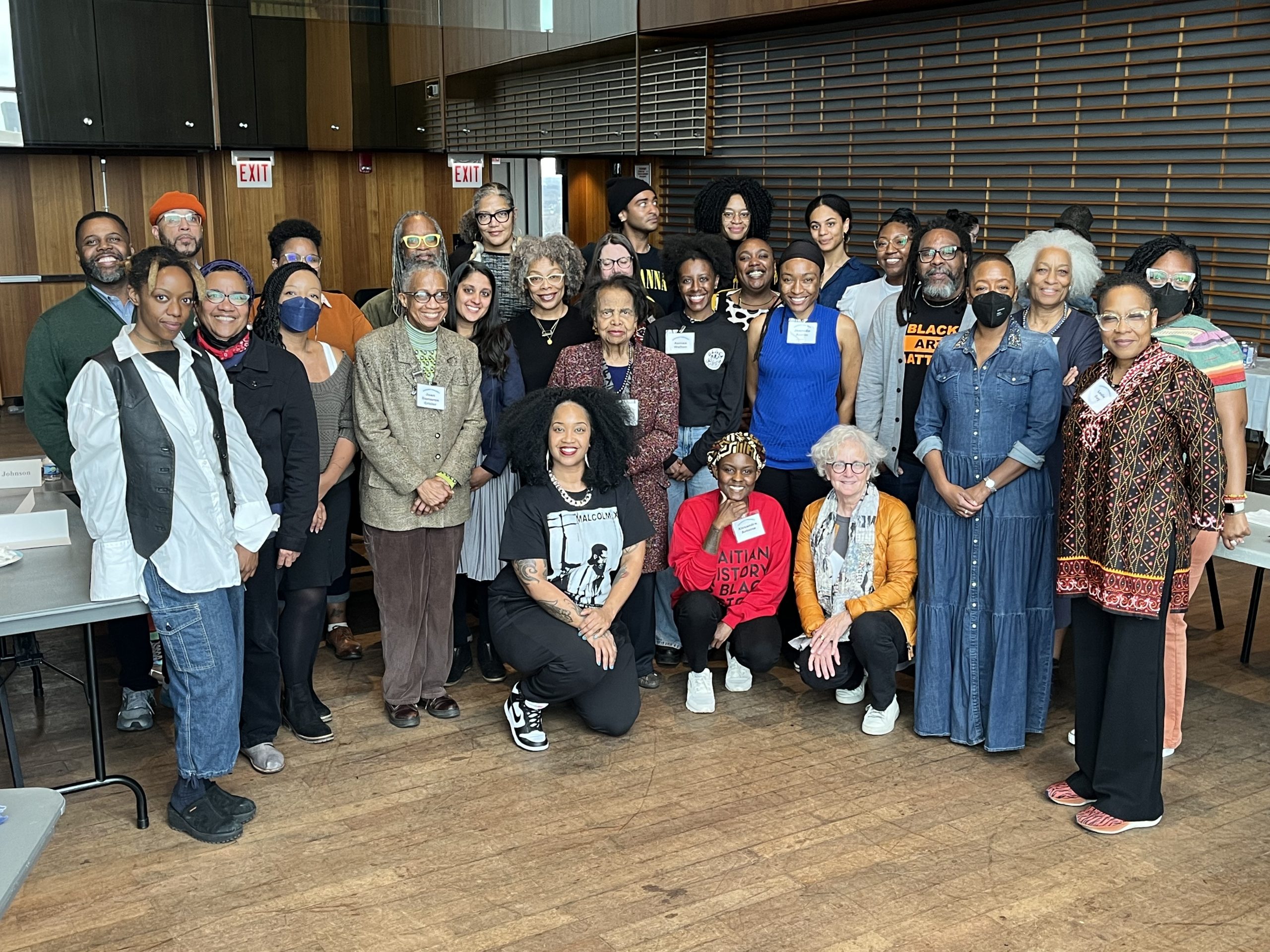 Image: The participants of the CONDUIT gathering, posed for a photograph indoors. The floor is light wood. Photo by John Austin Davis.