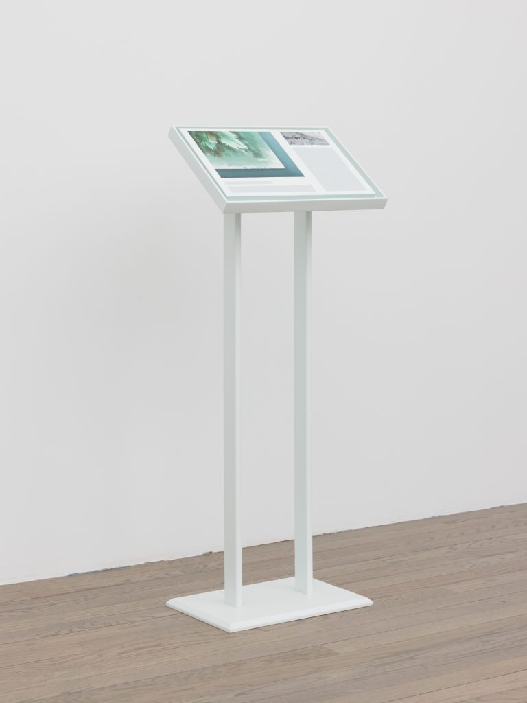 A white stanchion sits in a gallery space, displaying two, cropped detail images and two horizontal, blank rectangles. Image courtesy of Patron Gallery. Photographer Evan Jenkins.