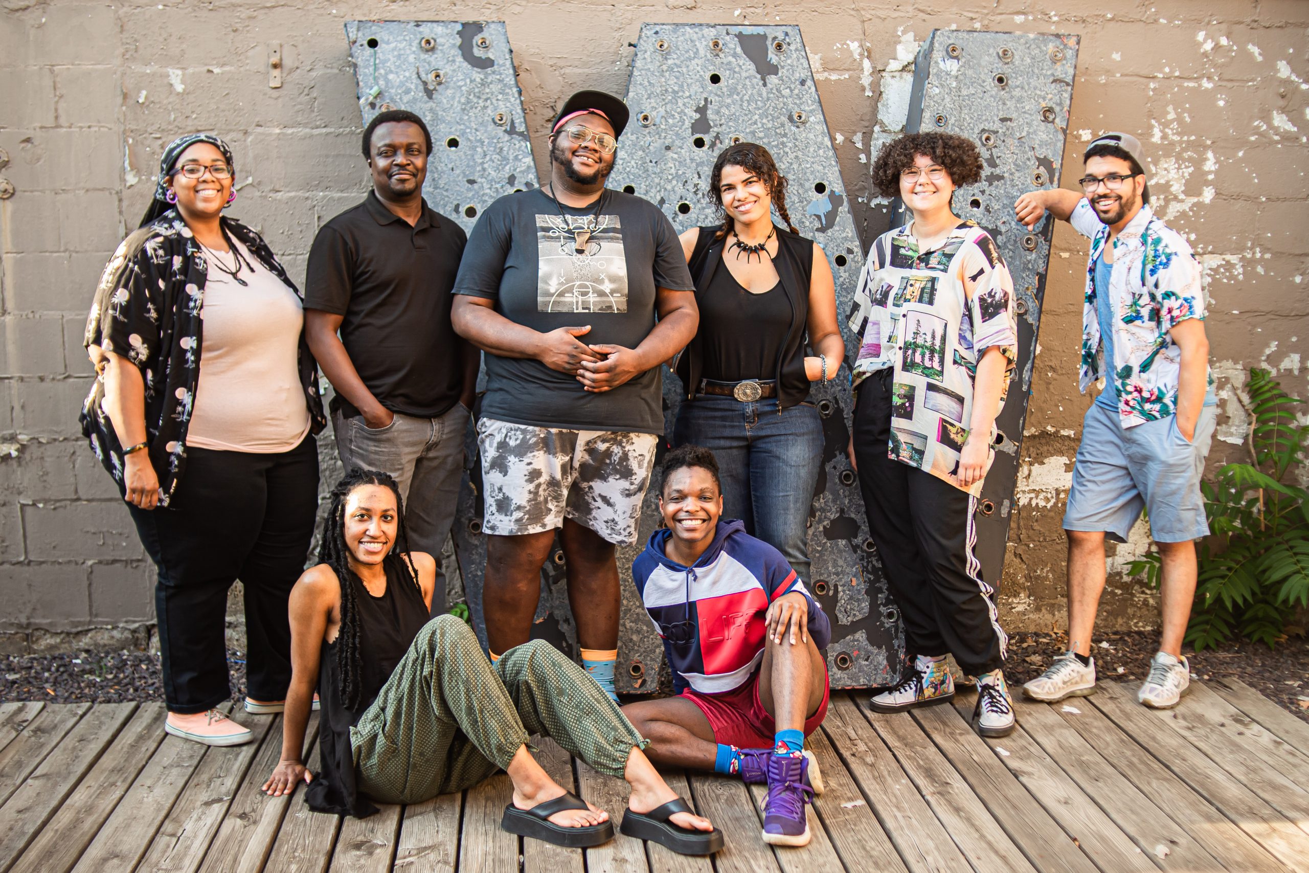 Eight members of PGOBA stand outdoors, smiling and glowing with a large W behind them—photo by Alexa Crary.