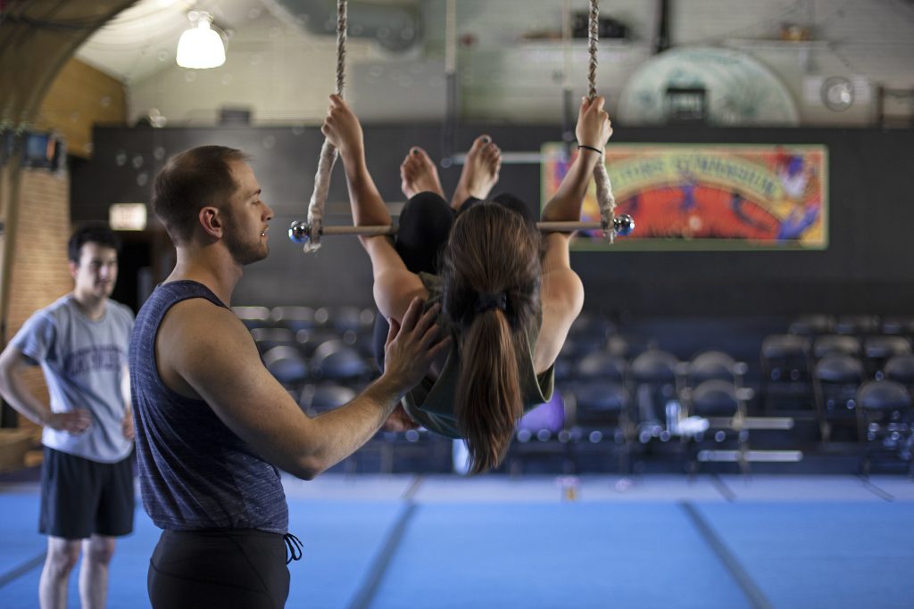 Image: A teacher helps a student position themselves on a swing during an acrobatic lesson at The Actors Gym. Image courtesy of The Actors Gymnasium.