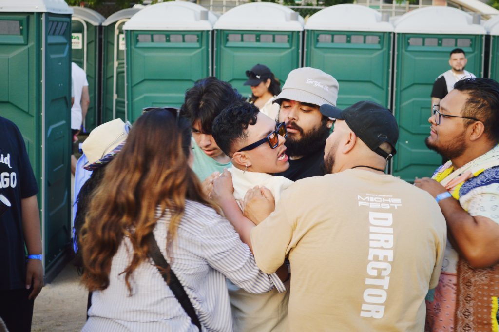 Image: A person being escorted out of Miche Fest for probably drinking too many micheladas and wanting to fight, 2023. Photo by Luz Magdaleno Flores