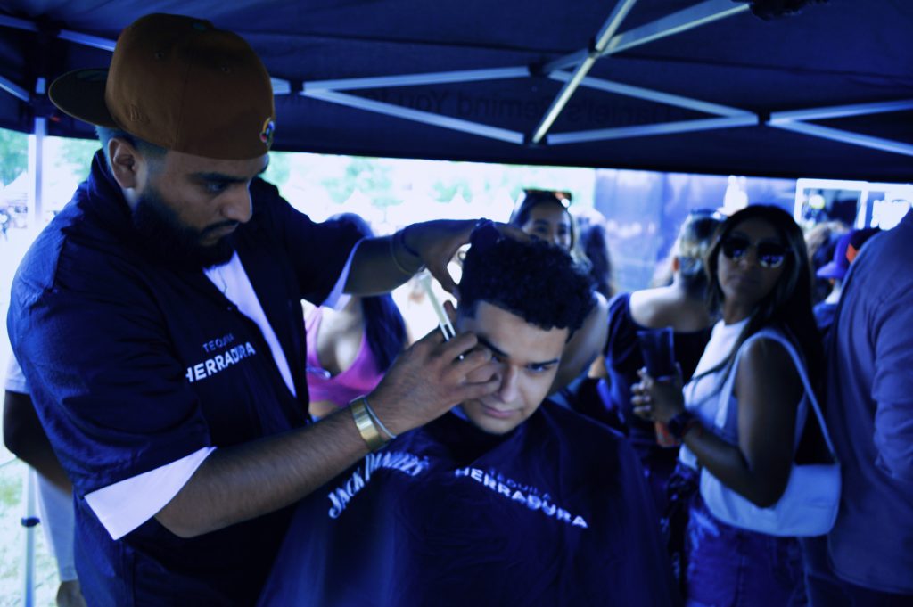 Image: Festival attendee, Javi getting a haircut by Temo at the Tequila Herradura pop-up at Miche Fest, 2023. Photo by Luz Magdaleno Flores