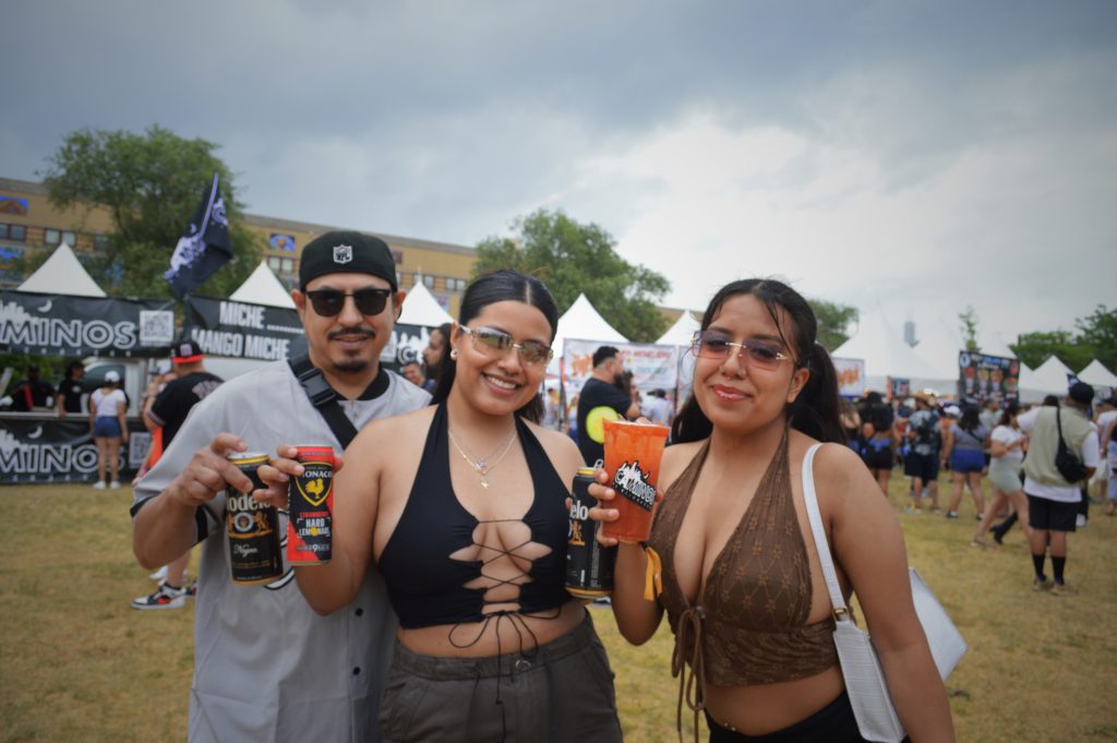 Image: Three brown people smiling and holding two Negra Modelo's, a Monaco, and Camino's Michelada at Miche Fest, 2023. Photo by Luz Magdaleno Flores