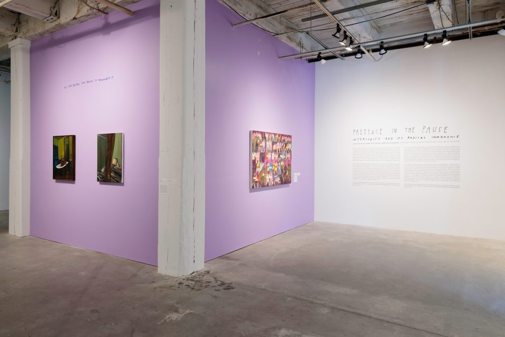 Image: Installation photo of Presence in the Pause: Interiority and its Radical Immanence. Danielle McKinney’s "Fly High" and "Calvary" paintings hang on the left with a light purple background.  Andrea Joyce Heimer's painting "I Fight Myself Over And Over And Over And Over And Over Again" is displayed in the middle. The exhibition text is displayed on the right. Image courtesy of Bemis Center For Contemporary Arts.
