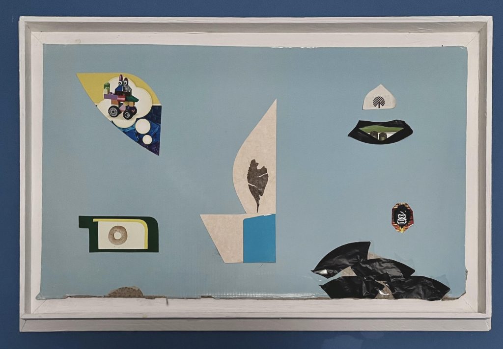 Image: Thomas’ work is float-mounted to a white frame against navy blue background. Thomas’s work entails six small collages on muted baby-blue cardboard. Larry’s text, below, describes detailed information about the artwork. Photograph by Larry Lee.