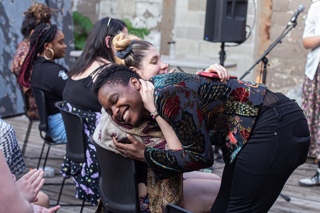 Image: Ezra Collom hugs a member of the crowd after singing as part of the CANJE open mic. Photo by Alexa Cary.