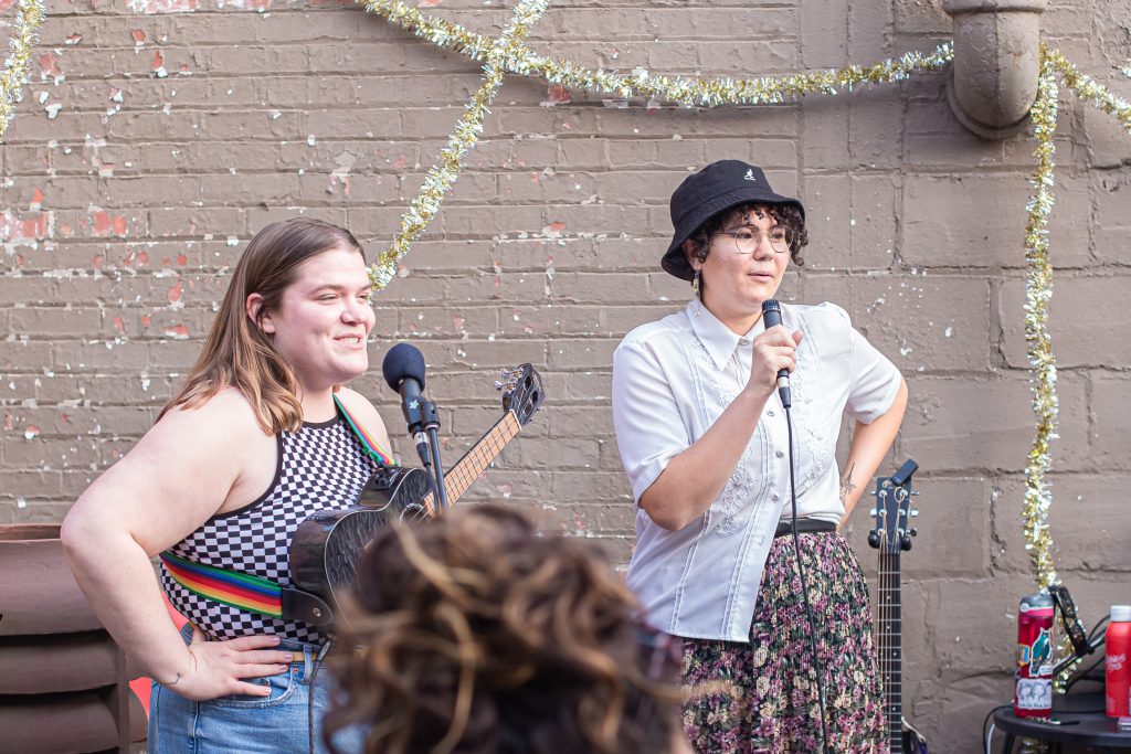 Image: Cami Proctor can be seen on the right speaking into a microphone right before the person on the left performs. Photo by Alexa Cary.