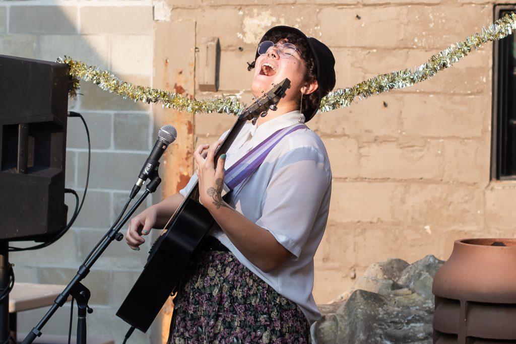 Image: Cami Proctor performs (sings and plays guitar) at the open mic they hosted as part of the second session of CANJE. Photo by Alexa Cary.