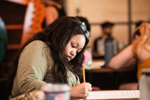 Image: Autumn Angelize sits and writes notes/feedback for the participating artists of at CANJE Session 1: The Art of Critique. Photo by Alexa Cary.