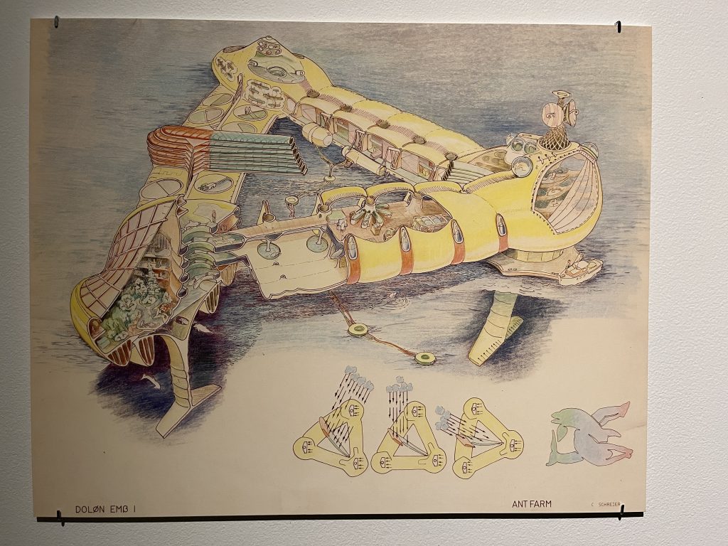 Image: Ant Farm, Dolphin Embassy, 1974-78, ephemera, facsimiles. A colorful schematic drawing of an imagined dolphin embassy. It is a triangular structure with a cross-section showing the inside. On the bottom of the drawing are three overhead views of the structure, with movement indicated by arrows. The structure is colored yellow. Photo by Jessica Hammie.