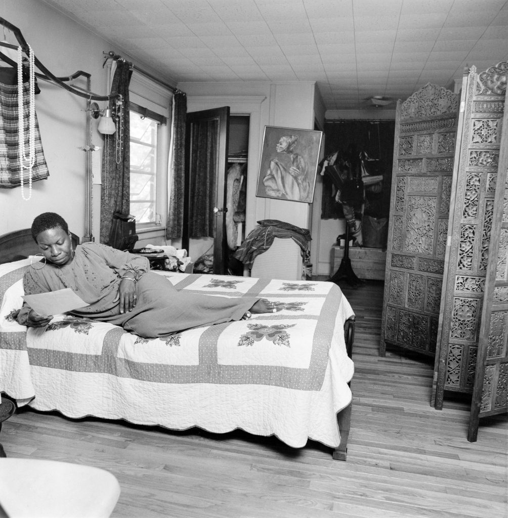 Image: Black and white photographic portrait of Nina Simone laying on her bed, relaxing at home. The photograph is in the Johnson Publishing Company Archive. Courtesy J. Paul Getty Trust and Smithsonian National Museum of African American History and Culture. Made possible by the Ford Foundation, J. Paul Getty Trust, John D. and Catherine T. MacArthur Foundation, The Andrew W. Mellon Foundation, and Smithsonian Institution.