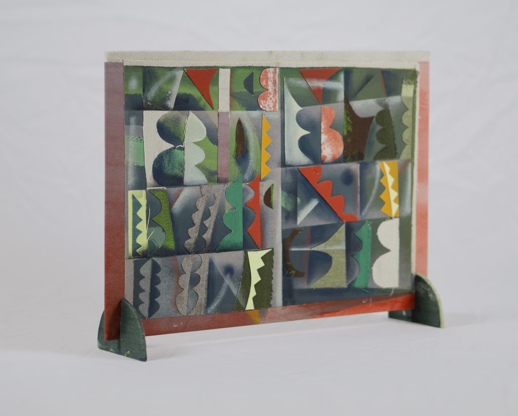 Photography: Independent panel of two open faced art pieces, supported by two lower green arched supports. The panel is painted on one side with geometric shapes and a predominantly green color palette. The other side of the panel has painted geometric shapes made of a predominantly red and orange color palette.