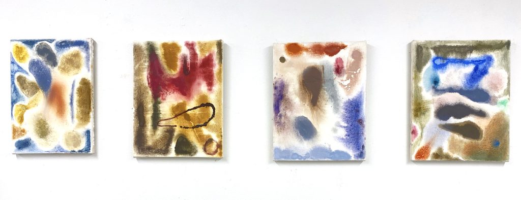 Image: Streams of Consciousness, Diana Motta. From left to right: a canvas with a white bloom dominating the right side of the canvas, a smudge of clay-orange in its center as finger-like structures arrive to its left; next, a brown and gold dominant painting, near its top a red crown-like figure sits in the center, while, beneath it, an oblong strong brown line shapes the gold; next, a lighter canvas with a brown upside-down pear shape in its center, surrounded by several splotches of lighter colors: a tan, a purple, a blue, a grey, a brown;  the final canvas features a bright blue shaped like a flattened "7" near the top of the canvas, beneath which are three layers of grey oblong, cloud-like shapes with mostly white space between them and on one side of the "7" is a soft blue splotch and, on the other side, is a pink splotch. The remainder of the canvas is shades of brown and gold. Image courtesy of the artist.