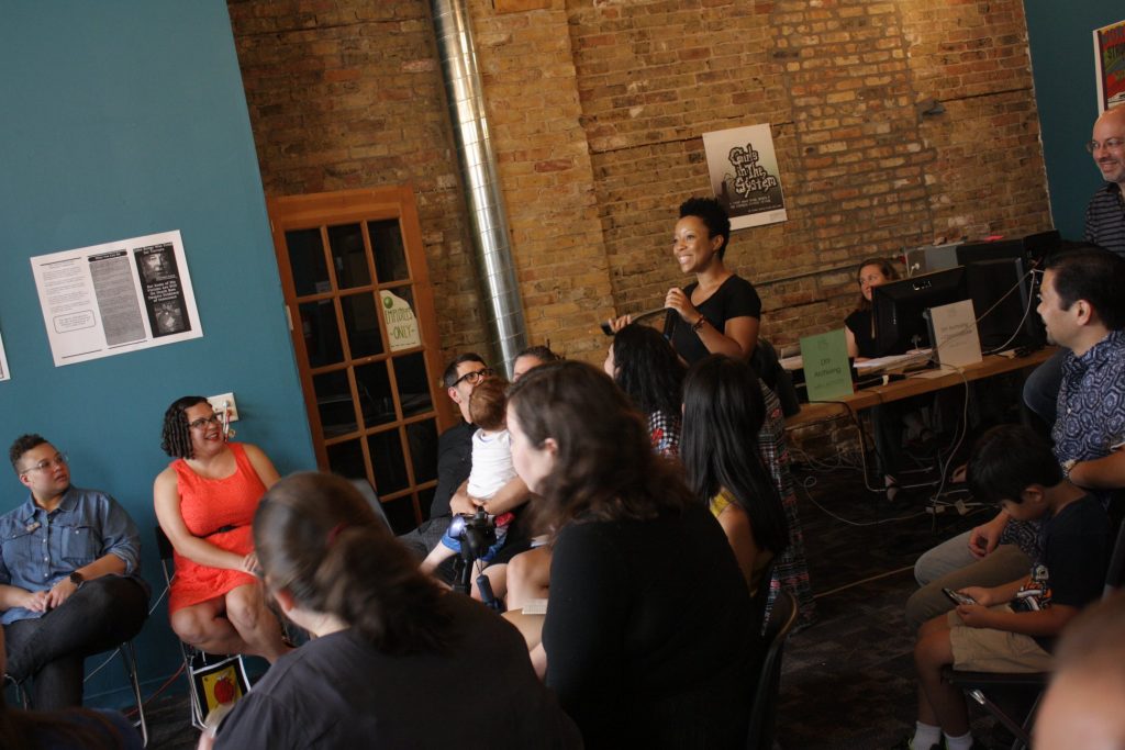 Image: Tempestt Hazel speaks during the 2018 Chicago Archives + Artists Festival. She stands in a room full of festival attendees. Photo by Hannah Siegfried.