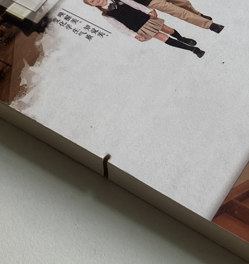 A detail image shows a notch made in the side of poetry book. The cover of the book has Chinese characters and two uniformed children partially visible. 