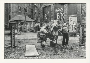 Imagen: Pilsen, circa 1991-1994, Fotografo: Akito Tsuda. Chicago Public Library, Colección Especial, Akito Tsuda Fotografia, Caja 1: Foto 1.57. En esta foto en blanco y negro, dos niños cuelgan al revés riendo.