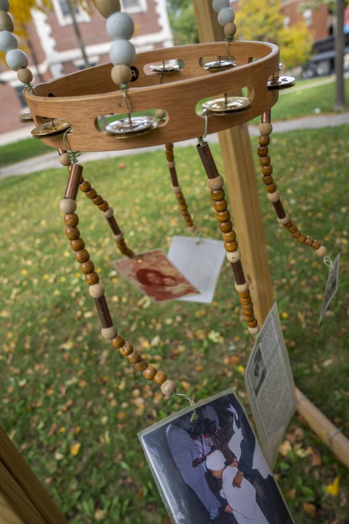 Image: …and it came like a vision in the night (dreaming delta blues from refuge to you), 2022 by Janelle Ayana Miller, installed as part of Finding Ceremony—Tiffany Johnson's project for her 2022 Anchor Curatorial Residency at Austin Town Hall. Strings of wooden beads hang down and connect to a tambourine. Hanging on the ends are photos. Image courtesy of Tiffany Johnson. Photographer: Vanessa Lara/ Colectivo Multipolar.