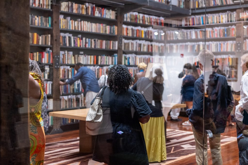 Image: Attendees stand, admire, and engage with the books from Johnson Publishing Company's editor library at Stony Island Arts Bank. Photo by Tonal Simmons.