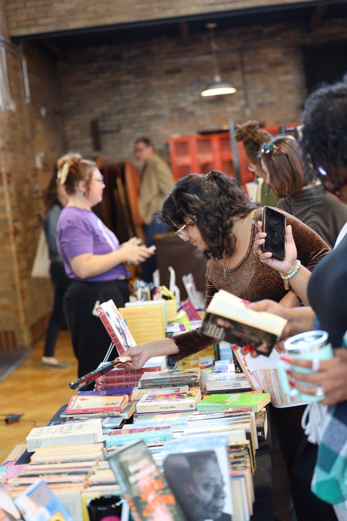 Image: A crowd of people peruse the different tables of books at Proof: A Midwest Lit Fest in Indianapolis, IN. Photo credit: Indiana Humanities.