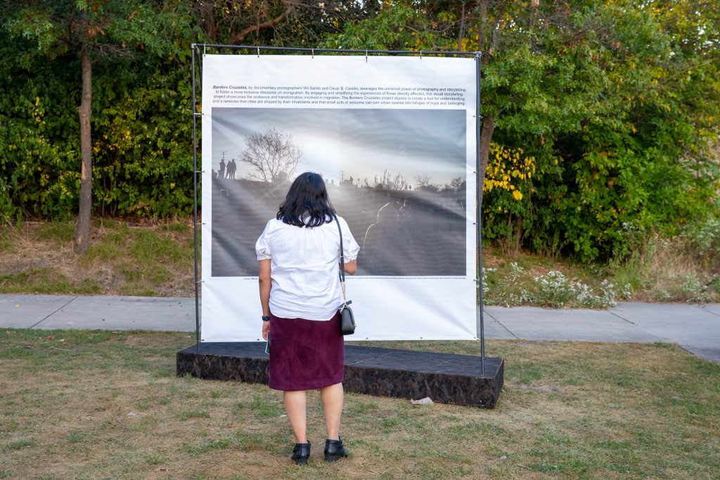 Image: Onlooker viewing installation by ART WORKS Projects. The installation shows a large photo with text above it. Lush foliage covers the background. Photo by Ruby Que. 