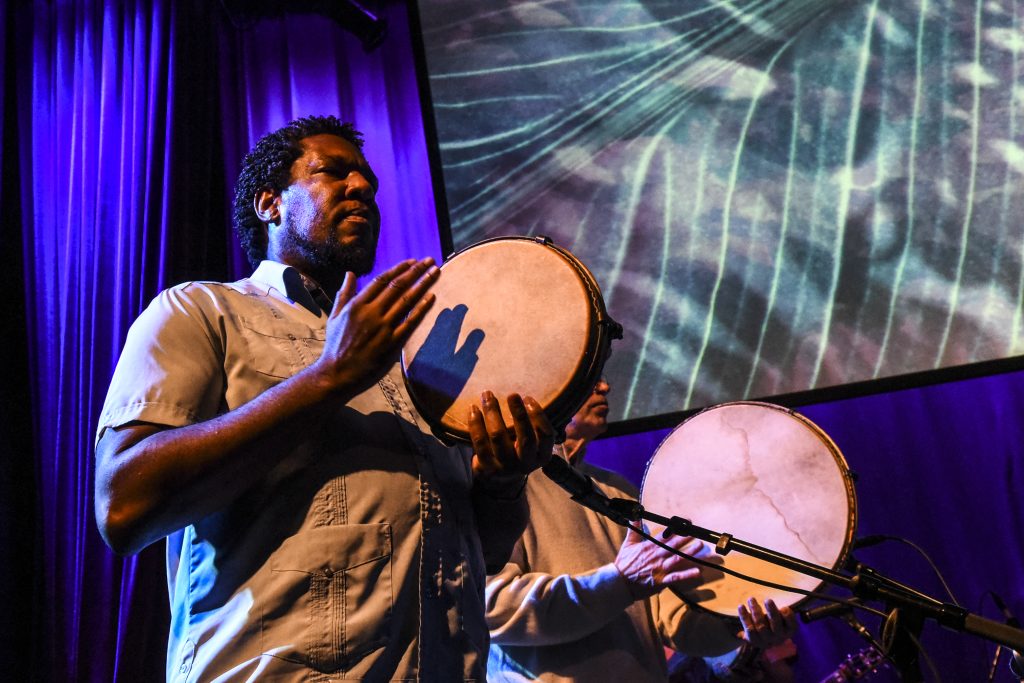 Image: Foto of a member of Africaribe playing the traditional Puerto Rican hand drum the pandero, delivering a dynamic rhythm to the performance. Digital foto by Carolina Sánchez.