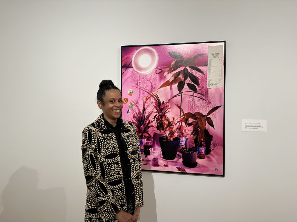 Right Image: A photograph of Samantha Box standing in front of Transplant Family Portrait, 2020
Digital collage printed as archival inkjet print, collaged with secondary archival inkjet print elements. Transplant Family Portrait features a collection of potted plants and various hues of pinks. Image courtesy of the Des Moines Art Center.