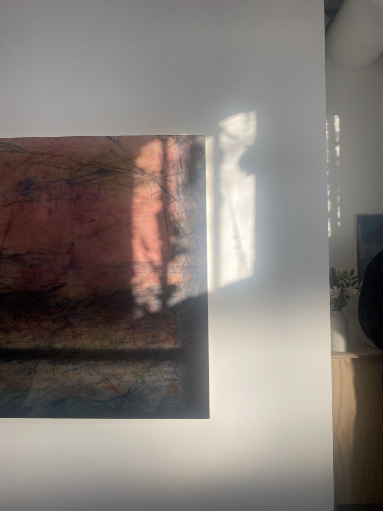 Image: Installation photo of  Helen, 2024, by Yifan Li during the opening exhibition Visages of Time at Goldfinch Gallery. Optional to include: Photo only shows right third of the work. Patterns of light from the afternoon sun shine in the upper right corner of the work. There is a small parallelogram that shines onto the exhibition wall. Sunlight dapples in the small corner to the right of the wall. A pocket of light reveals a bouquet on a raw wooden shelf. Photo by Joan Roach.