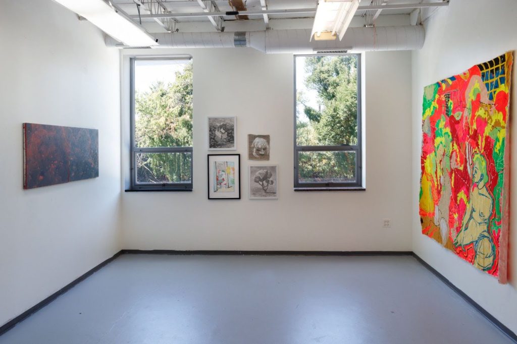 Image: A gallery wall view of Preface / ... yet flavourful. On the right is an acrylic on canvas piece by Dasha Shishkin depicting a vibrant and chaotic composition dominated by red, yellow, and green hues. It features abstract human figures, some in motion, with a seated, outlined figure on the right. The scene appears fragmented and layered, with overlapping elements and bold brushstrokes. Photo by Tianjiao Wang.
